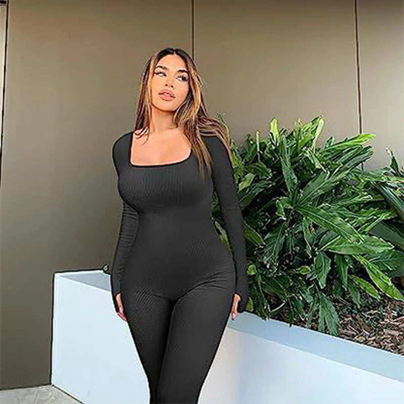 Woman modeling a seamless long-sleeve yoga jumpsuit against a leafy background.