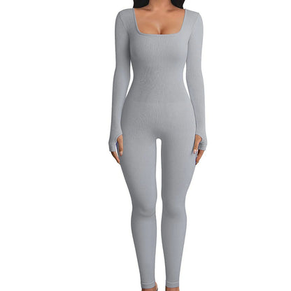Model wearing a seamless long-sleeve yoga jumpsuit in gray, perfect for workouts and lounging.
